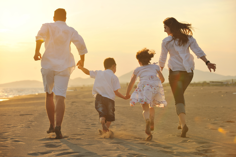 happy young family have fun on beach run and jump  at sunset